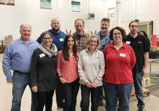 The Schramm Construction Corp. team poses for a lighthearted photo during a volunteer project at the Northern Illinois Food Bank, one of many charities supported by the St. Charles, Illinois-based company.